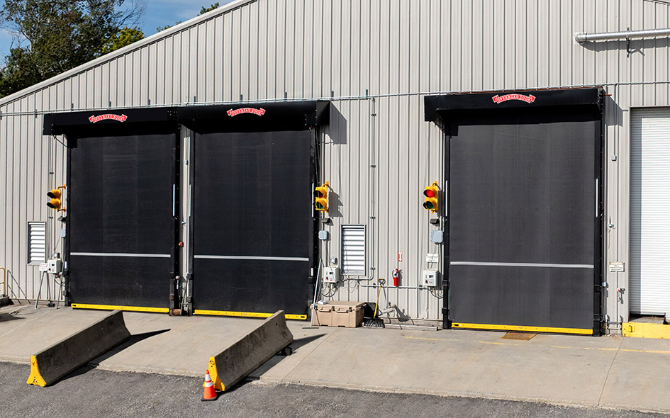 three black rubber commercial doors on a gray commercial building
