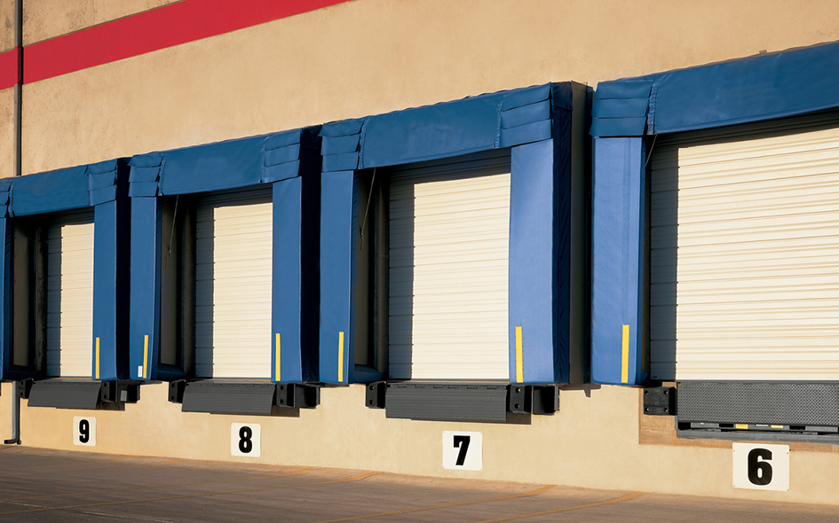 white sectional steel commercial doors with blue dock padding